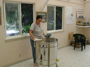 and prepare for extraction process.
						 Krsna Priya Didi cleans the honey harvesting machine.