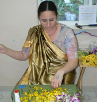 The garland seva is ongoing, here Krishnapriya Didi sews garlands for the small Deities.