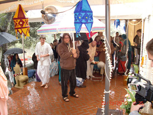 Phalguni Krishna Prabhu holds his large umbrella to offer shelter to the devotees offering flowers.